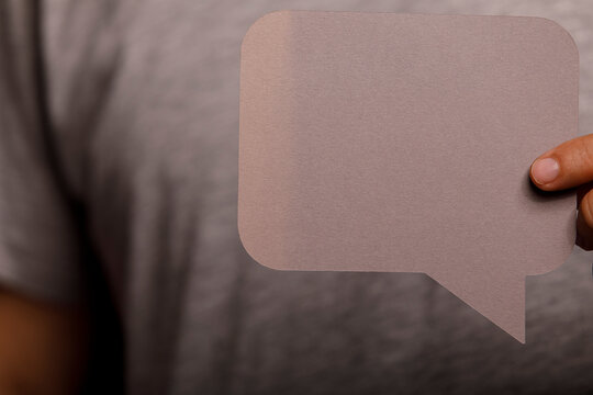 A person holds a blank grey speech bubble, ready for your custom message or icon.