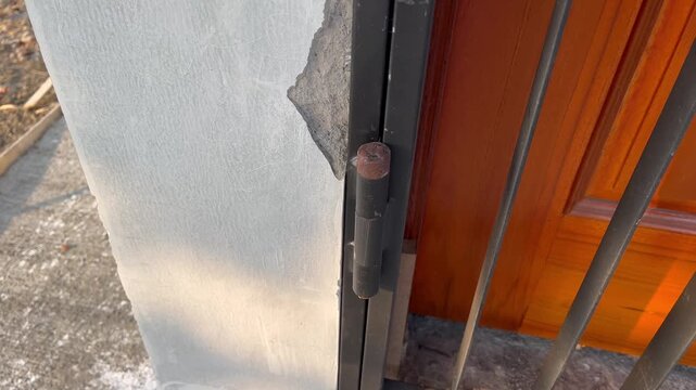 Heavy duty iron gate hinge on cracked concrete wall