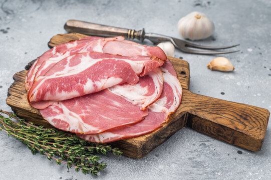 Italian coppa capicola pork slices with thyme on a rustic wooden board over a gray stone background perfect for gourmet food stock images.