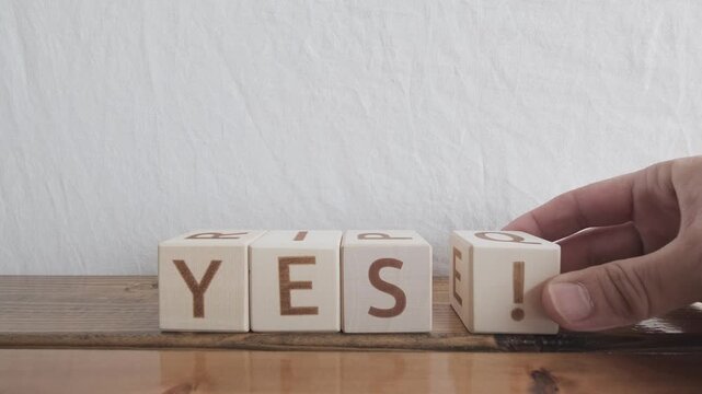 motivational word Yes!, laying out by hand from letters on wooden cubes, slow motion
