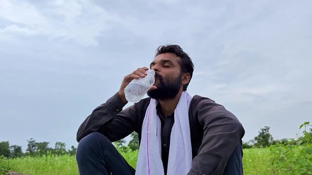 Thirsty indian farmer drinking water from bottle
