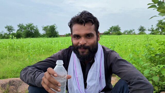 Thirsty indian farmer drinking water from bottle