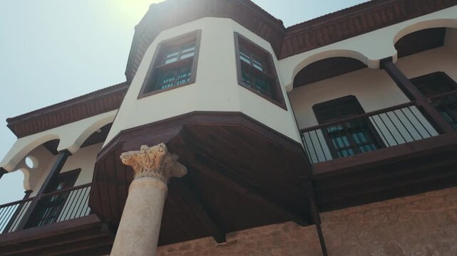 Low angle pan shot of historic Ottoman mansion facade with traditional wooden bay window supported by marble column