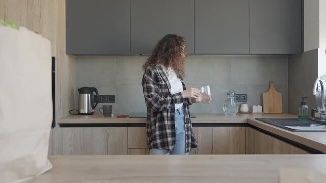 Woman Drinking Water In Kitchen After Grocery Shopping