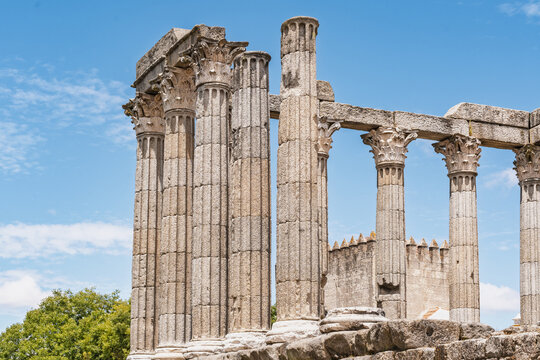 View of the Roman Temple of Evora with its ancient Corinthian columns standing against a clear blue sky in Evora, Evora District, Portugal.
