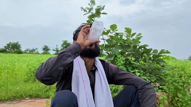 Thirsty indian farmer drinking water from bottle