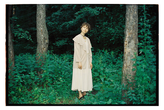 Woman standing in the forest surrounded by green plants