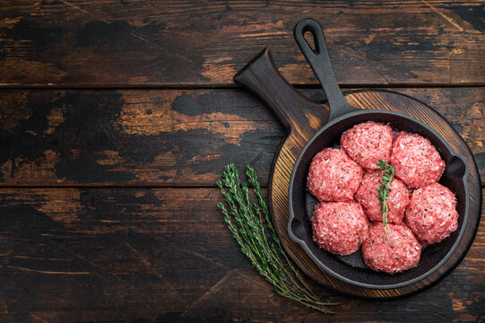 Groundmeat meatballs or Frikadel in cast iron pan on wooden board offering detailed texture ideal for grocery, cooking and nutrition imagery.