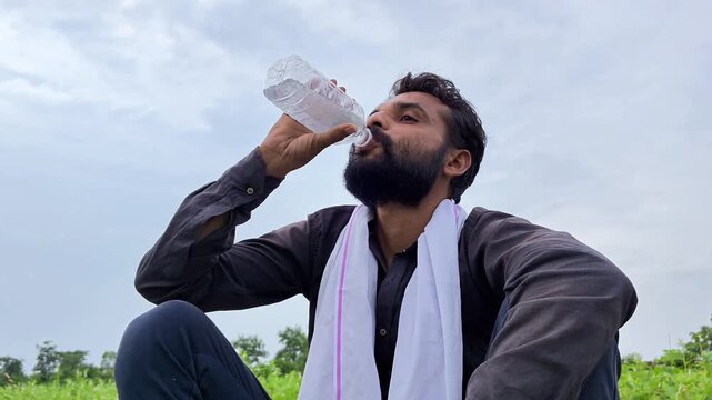 Thirsty indian farmer drinking water from bottle