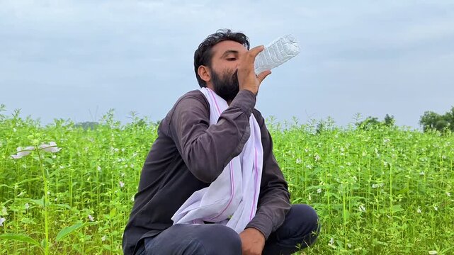 Thirsty indian farmer drinking water from bottle