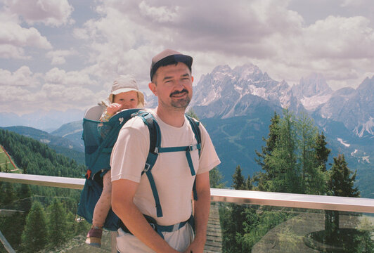 Portrait of a happy father with child in a backpack carrier