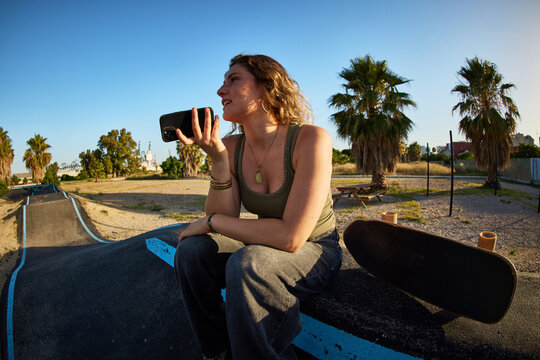 Skater sitting on a ramp while talking on a phone in a park