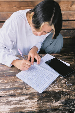 Girl studies Korean while sitting at a wooden table outdoors