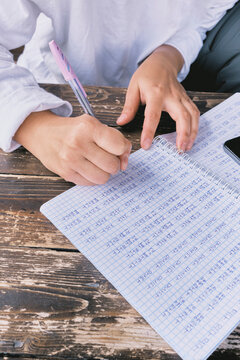 Girl studies Korean with notebook and pen at wooden table