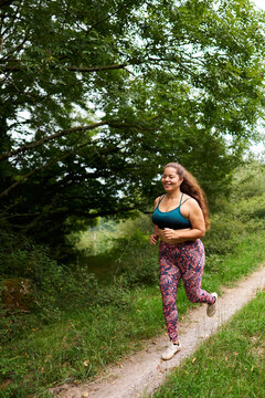 Plus size woman jogging in forest trail