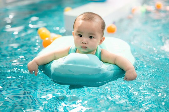 Baby Floating in Pool by colorful toys
