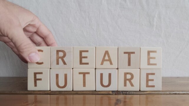 motivational word Create future, laying out by hand from letters on wooden cubes, slow motion
