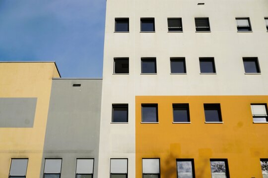 Fassade von beige-grau-braunem Krankenhauskomplex mit Flachdach und fenstern vor blauem Himmel bei Sonne am Nachmittag im Sommer
