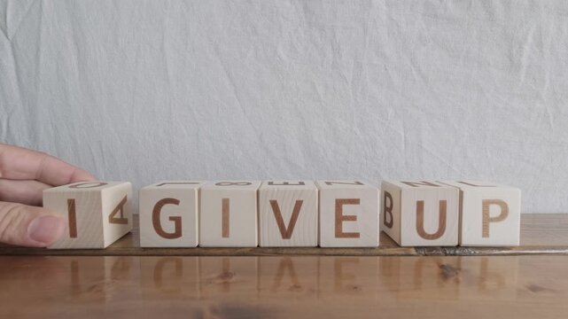 motivational word I give up, laying out by hand from letters on wooden cubes, slow motion
