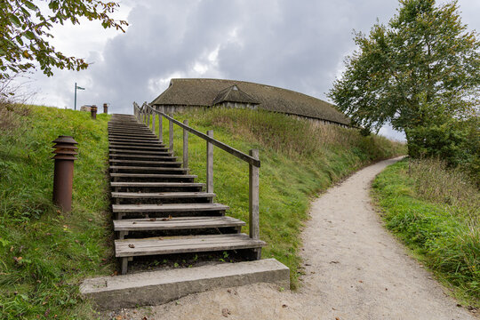 View of the reconstructed Viking longhouse at The Viking Museum Fyrkat with wooden stairs leading up the grassy embankment in Hobro, Jutland, Denmark.