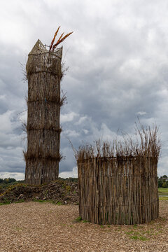 View of the tall woven stick tower and circular enclosure at Fyrkat Viking Museum under a cloudy sky in Hobro, Jutland, Denmark.