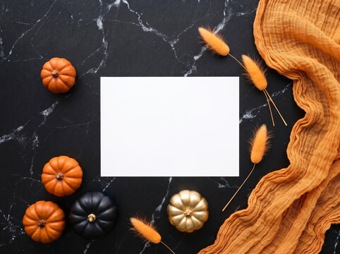 Blank card mockup surrounded by miniature pumpkins and autumn grasse on a dark marble surface