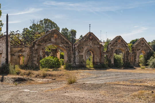 View of the historic ruins of the Minas de Sao Domingos industrial site featuring stone arches and weathered walls under a clear blue sky in Corte do Pinto, Beja District, Portugal.