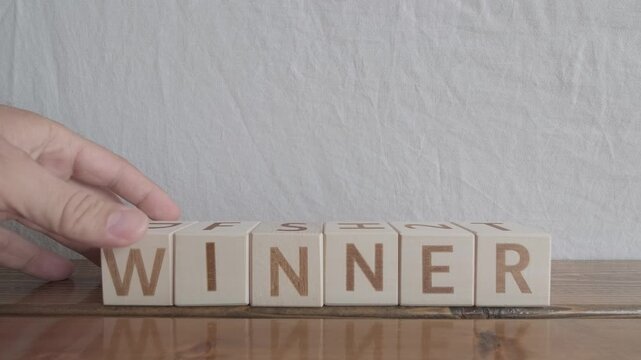 motivational word Winner, laying out by hand from letters on wooden cubes, slow motion
