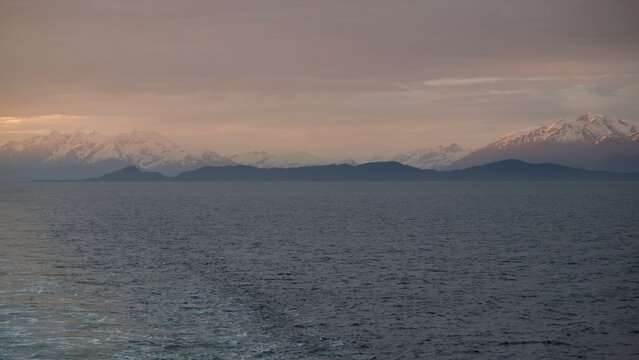 Breathtaking Alaska mountain glacier range view seen from outdoor deck of cruise ship liner sailing the Inside Passage transit with spectacular landscape scenery during sunset