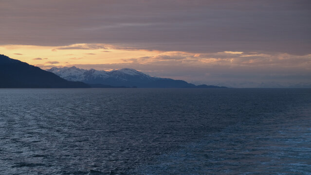 Breathtaking Alaska mountain glacier range view seen from outdoor deck of cruise ship liner sailing the Inside Passage transit with spectacular landscape scenery during sunset