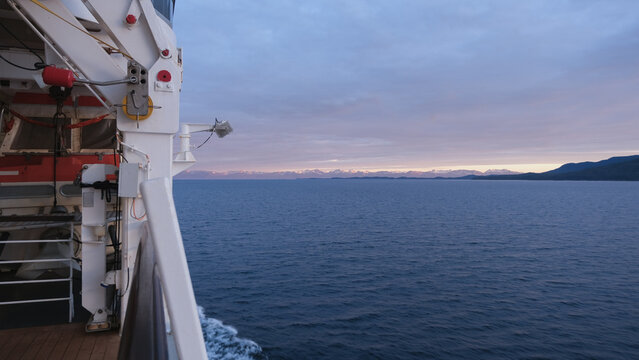 Breathtaking Alaska mountain glacier range view seen from outdoor deck of cruise ship liner sailing the Inside Passage transit with spectacular landscape scenery during sunset