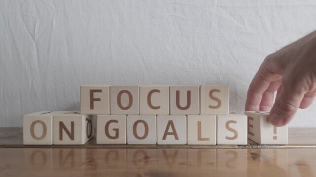 motivational word Focus on goals!, laying out by hand from letters on wooden cubes, slow motion
