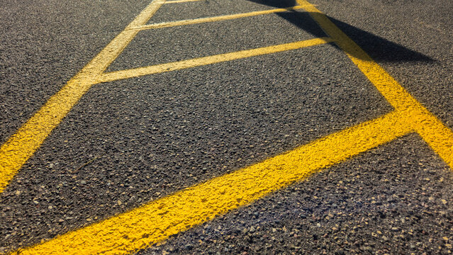 yellow painted pavement markings on asphalt surface, no-parking zone, a safety buffer, or accessible loading area. abstract background