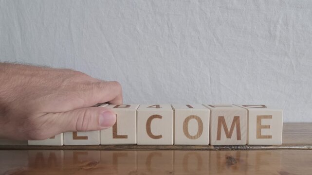 motivational word Welcome, laying out by hand from letters on wooden cubes, slow motion
