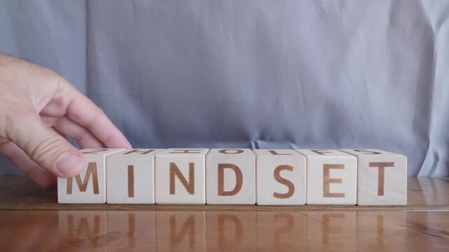 motivational word Mindset, laying out by hand from letters on wooden cubes, slow motion
