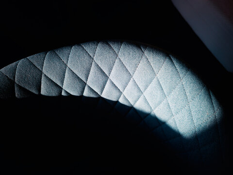 Dramatic light on the spherical blue fabric of arm-chair