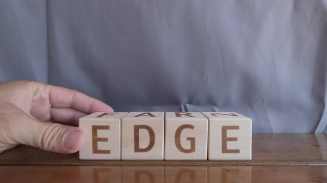 motivational word Edge, laying out by hand from letters on wooden cubes, slow motion
