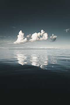View of calm sea waters reflecting white clouds under a clear horizon in Merikula, Harju maakond, Estonia.