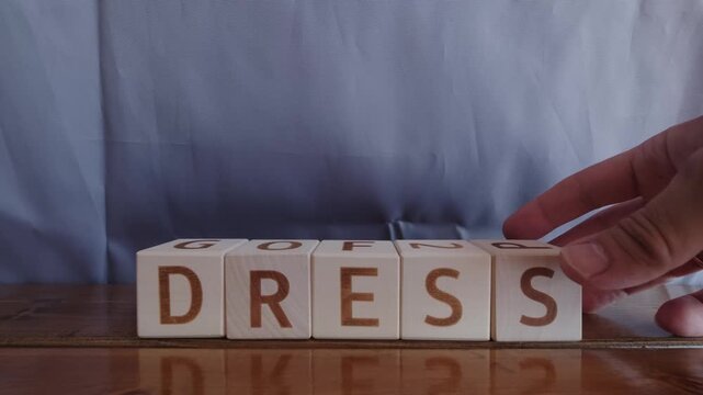 motivational word Dress, laying out by hand from letters on wooden cubes, slow motion
