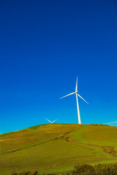 Wind Turbines on Green Rolling Hills Under Clear Blue Sky