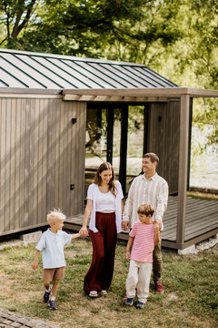 Family stroll by the modern cabin in a serene outdoor setting near water