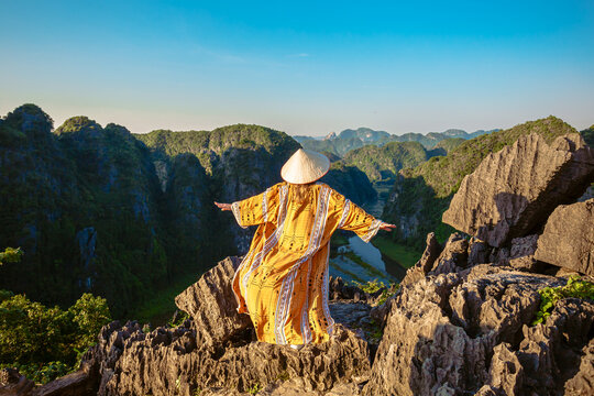 A young woman admires the  panorama of limestone rocks from Hang Mua Mountain. Ninh Binh Province, Vietnam.