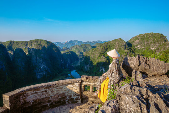 A young woman admires the  panorama of limestone rocks from Hang Mua Mountain. Ninh Binh Province, Vietnam.