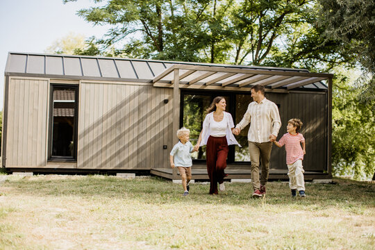 Family enjoying a sunny day walking in front of their modern cabin home