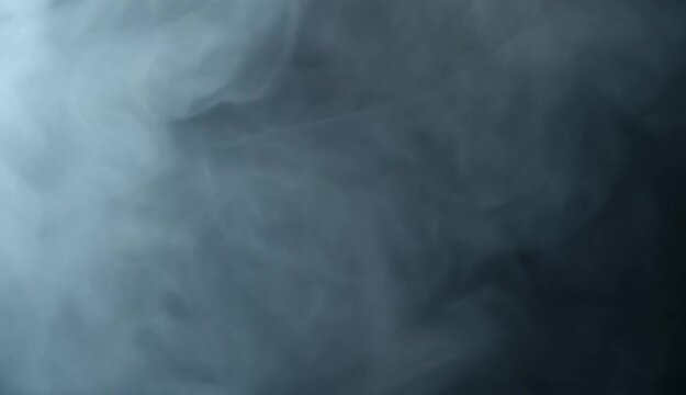 Wisps of white smoke drift and swirl in atmospheric darkness with subtle lighting for abstract backgrounds