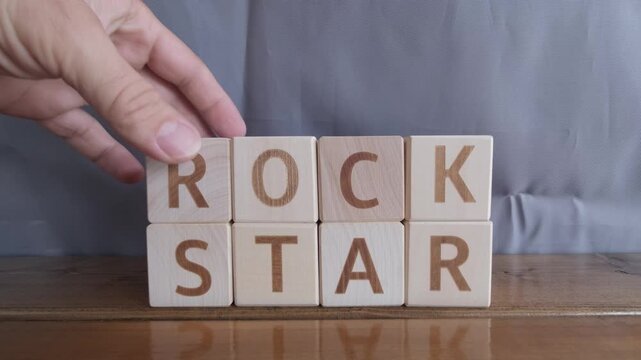 motivational word Rock star, laying out by hand from letters on wooden cubes, slow motion
