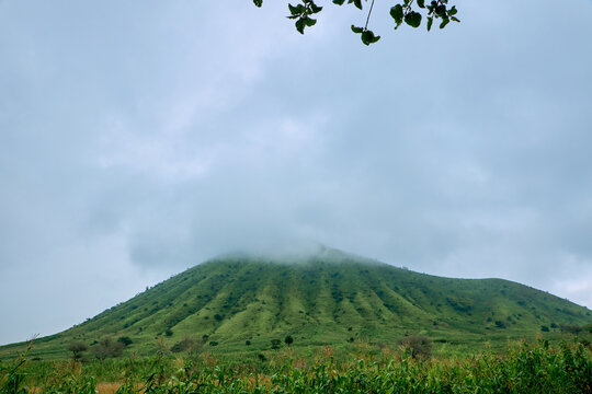 View of the Kerang volcanic cone with its distinctive green ridges under a cloudy sky in Kerang, Plateau, Nigeria.