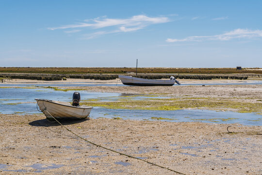 View of small fishing boats resting on the mudflats at low tide in the Ria Formosa lagoon, Tavira, Faro District, Portugal.