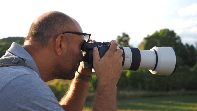 Male photographer using a professional telephoto lens to photograph wildlife outdoors