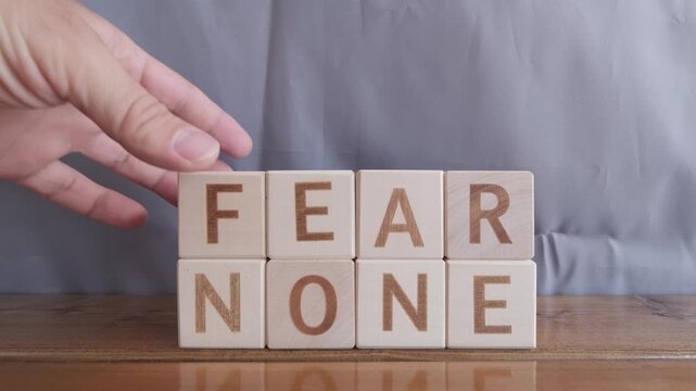 motivational word Fear none, laying out by hand from letters on wooden cubes, slow motion
